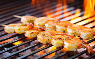 Garnelenspieße, die auf einem Grill über offener Flamme gegart werden - perfekt für Ihr nächstes BBQ-Catering oder Partyservice.