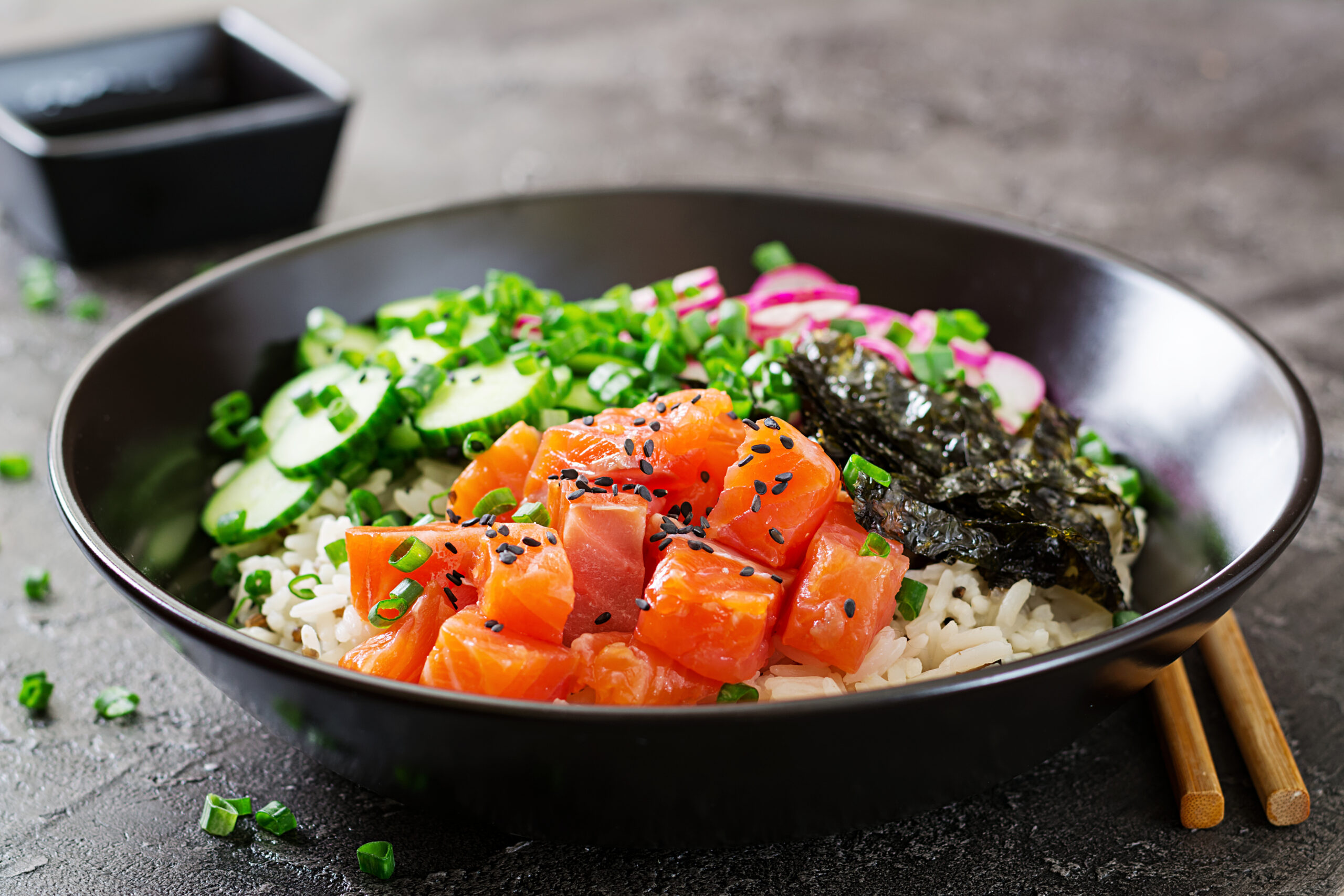 hawaiian salmon fish poke bowl with rice, radish,cucumber, tomato, sesame seeds and seaweeds. buddha bowl. diet food