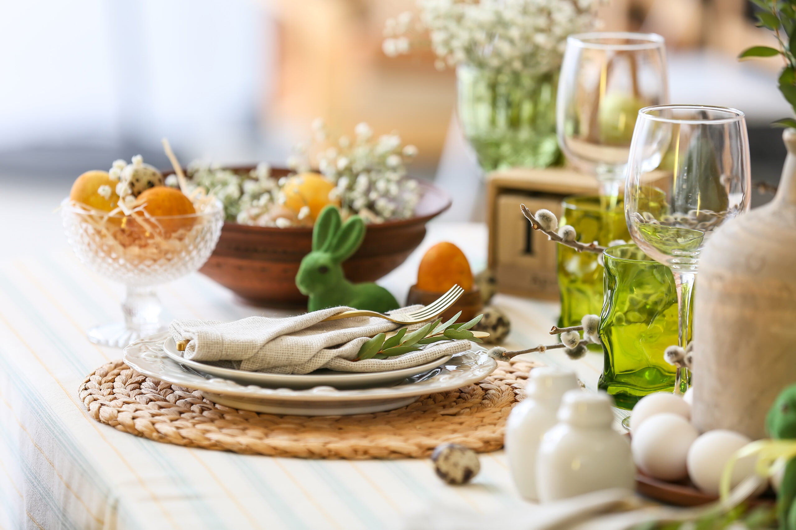 plates with napkin, cutlery and eucalyptus branch on table served for easter celebration